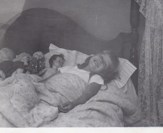 Christy with her dolls in bed
